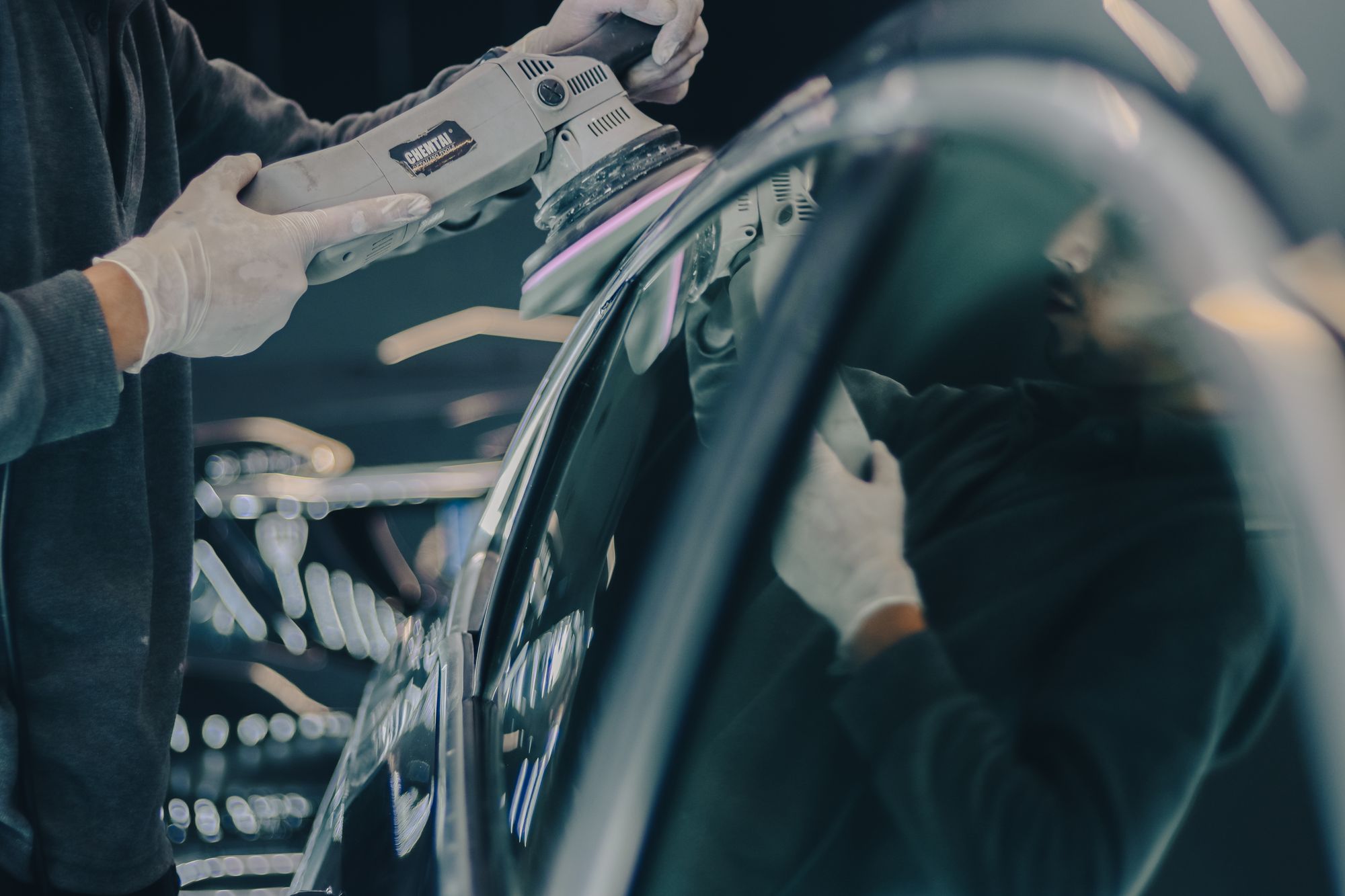 A polishing machine moving across a dark vehicle panel